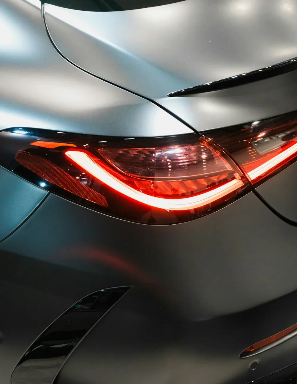 Gros plan du feu arrière LED d'une berline premium gris mat, coffre et aile visibles